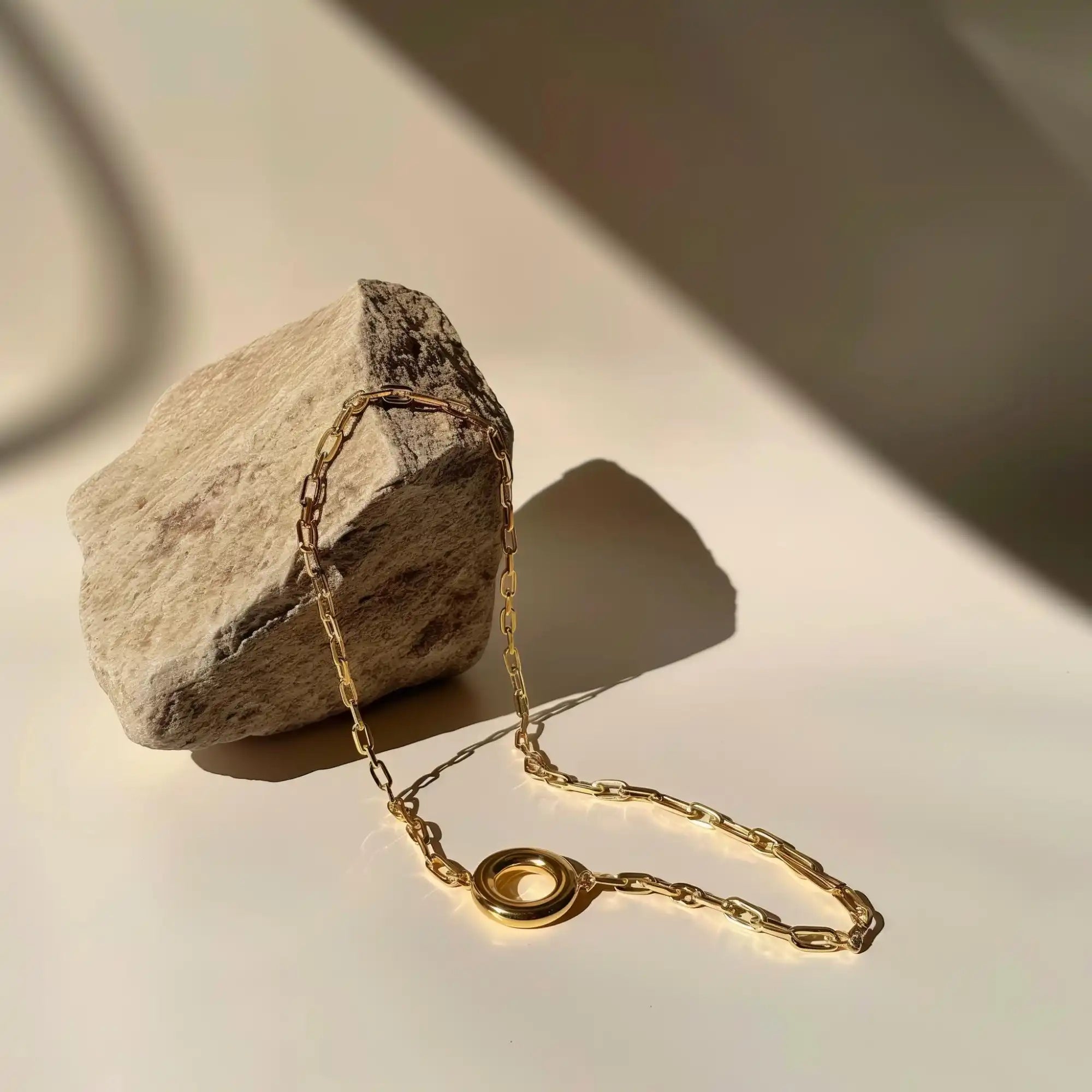 Gold chain necklace with circular pendant.